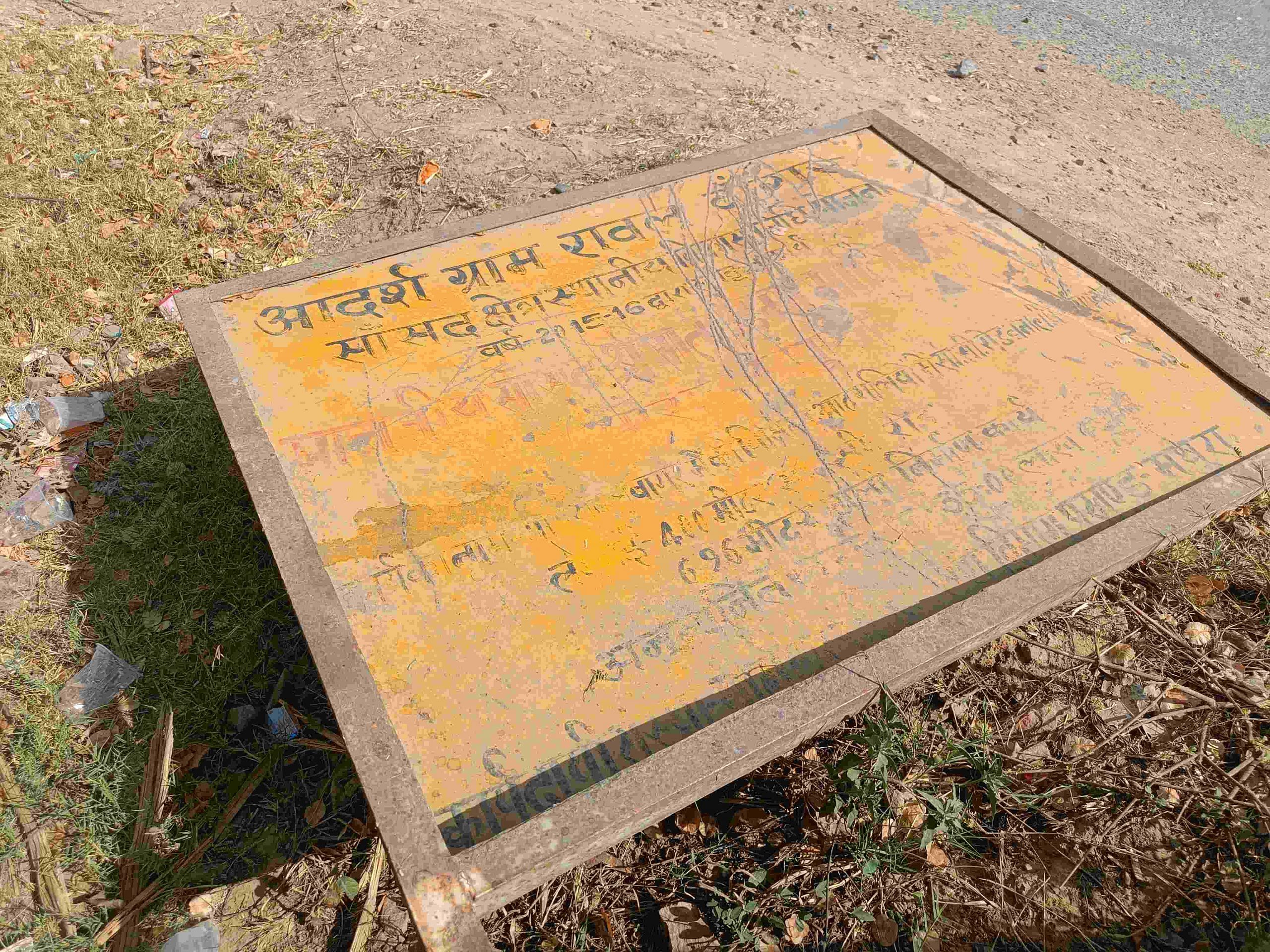 Iron board with the words 'Sansaad Adarsh Gram Yojana' lies on the road at the entrance of Rawal village | Krishan Murari | ThePrint