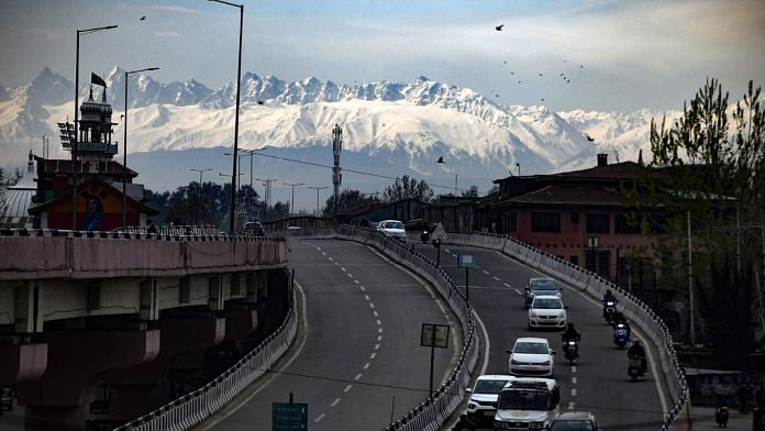 Vehicles ply on the road against the backdrop of snow-capped mountains in Srinagar | Photo: ANI/Imran Nissar