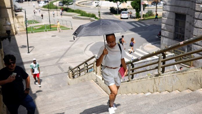 A woman protects herself from the sun with an umbrella during a heatwave in the centre of Sao Paulo, Brazil March 15, 2024 | Reuters