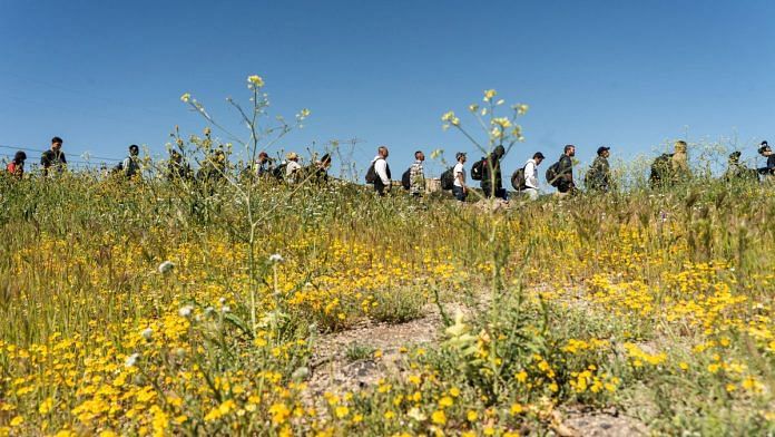 Asylum-seeking migrants line up near the border while waiting to be transported by the U.S. Border Patrol after crossing the border from Mexico into the U.S. in Jacumba Hot Springs, California, U.S. April 29, 2024. REUTERS/Go Nakamura