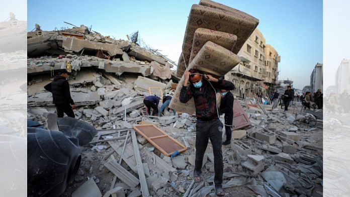 A man carries mattresses as Palestinians inspect the damages at the area around Al Shifa Hospital | Reuters /Dawoud Abu Alkas