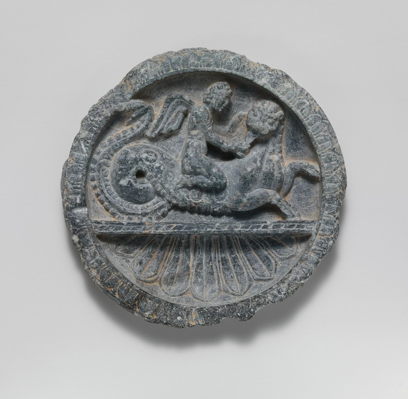 Dish with Winged Eros Riding a Lion-Headed Sea Monster, Pakistan (ancient region of Gandhara), 1st century BCE, Schist, 15.2 x 2.5 cm, Image courtesy of The Metropolitan Museum of Art, New York