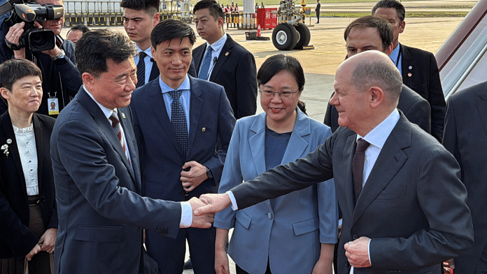 German Chancellor Olaf Scholz shakes hands with Chinese Ambassador to Germany Wu Ken next to Chongqing Vice Mayor Zhang Guozhi, upon arriving at the airport in Chongqing, China | Reuters/Andreas Rinke