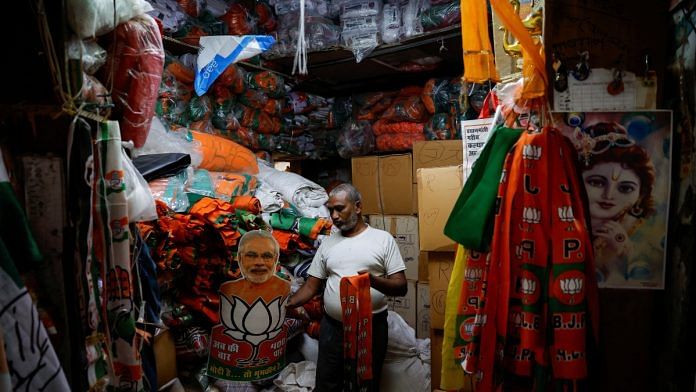 Alam Khan, 55, holds the cutouts of Prime Minister Narendra Modi and stoles of the ruling Bharatiya Janata Party inside a shop in Delhi, India, April 2, 2024 | Reuters