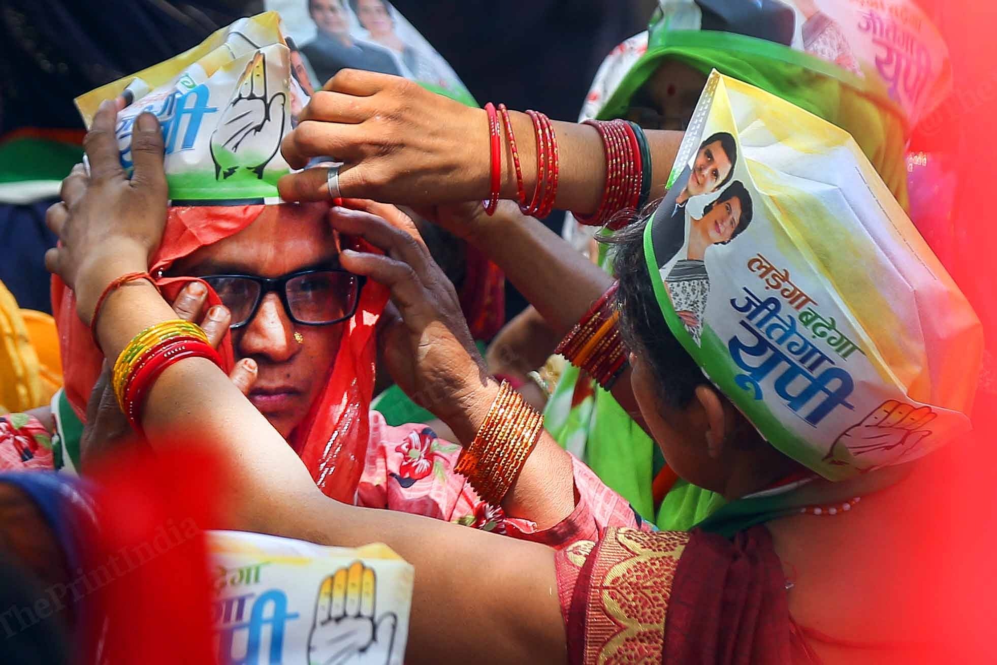 A woman helps another wear Congress cap | Suraj Singh Bisht | ThePrint