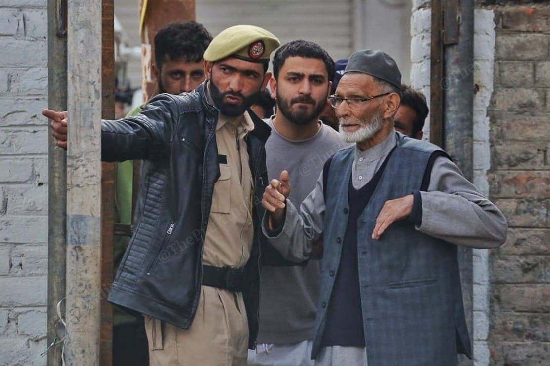 A policeman guiding an elderly man at a polling booth in Pulwama | Praveen Jain | ThePrint