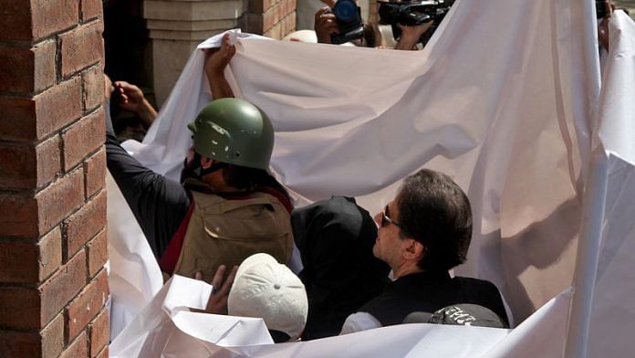 Pakistan's former Prime Minister Imran Khan and his wife Bushra Bibi are covered with a white sheet as they arrive to appear at the High Court in Lahore, Pakistan, May 15, 2023. REUTERS/Mohsin Raza/ File Photo