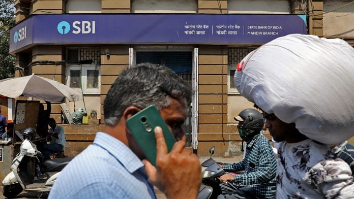 People move past a branch office of State Bank of India (SBI) in Mumbai, India | Representational image | Reuters