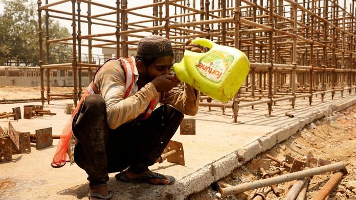 A construction worker drinks water from a container as he takes a break at a construction site during a hot summer day in New Delhi, India, May 22, 2024. REUTERS/Priyanshu Singh