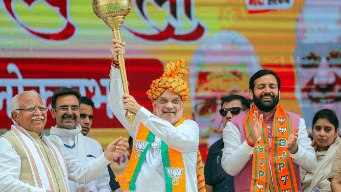 Union Home Minister Amit Shah holds a mace during a public meeting in Karnal. Haryana Chief Minister Nayab Singh Saini and former CM Manohar Lal Khattar also pictured | ANI