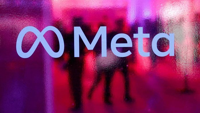 People walk behind a Meta logo | File Photo | Reuters