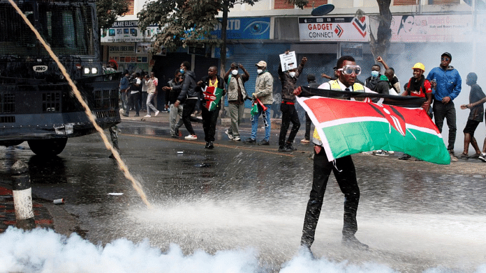 A demonstrator holds a Kenyan flag as police use water cannons and tear gas to disperse protesters during a demonstration against Kenya's proposed finance bill 2024/2025 in Nairobi, Kenya, June 25, 2024. REUTERS/Monicah Mwangi