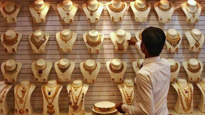 A salesman arranges a gold necklace inside a gold jewellery showroom in Kochi | REUTERS/Sivaram V/File Photo