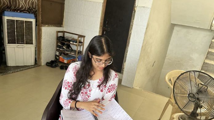 Surbhi Singh outside her one-room apartment, going through her notes | Photo: Nootan Sharma, ThePrint