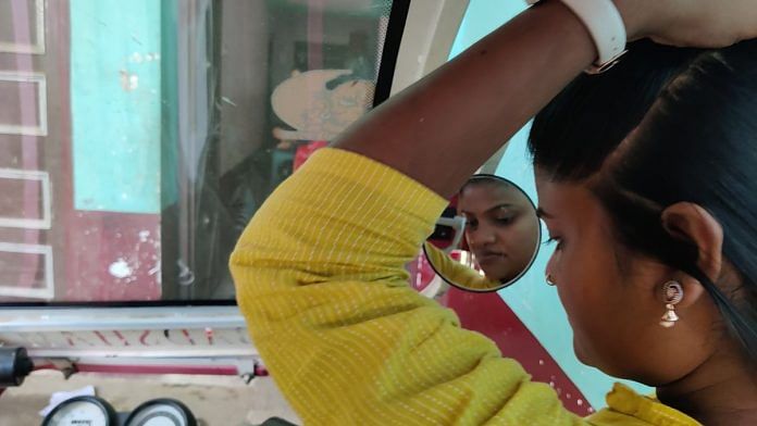Arti doing her hair with the help of her pink e-Rickshaw's side view mirror | Danishmand Khan, ThePrint