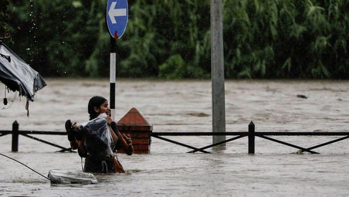 A woman carrying her belongings wades through a flooded road along the bank of overflowing Bagmati River following heavy rains in Kathmandu, Nepal, July 6, 2024. REUTERS/Navesh Chitrakar