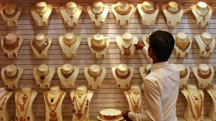 A salesman arranges a gold necklace inside a gold jewellery showroom in Kochi | File Photo/Reuters
