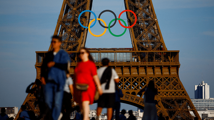 Tourists walk at Trocadero Square in front of the Olympic rings displayed on the first floor of the Eiffel Tower ahead of the Paris 2024 Olympic games | File Photo | Reuters/Sarah Meyssonnier