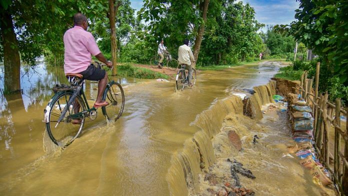 People ride their bicycle through a waterlogged road after rains, at Patiapum village in Nagaon district, Wednesday, July 3, 2024 | PTI