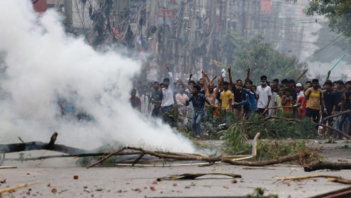 People gesture near smoke as protesters clash with Border Guard Bangladesh (BGB) and the police outside the state-owned Bangladesh Television as violence erupts across the country after anti-quota protests by students, in Dhaka, Bangladesh, July 19, 2024 | Reuters