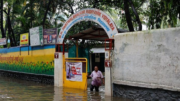 A man stands at the entrance of a school on a waterlogged street after heavy rains in Mumbai, India, July 8, 2024 | Reuters