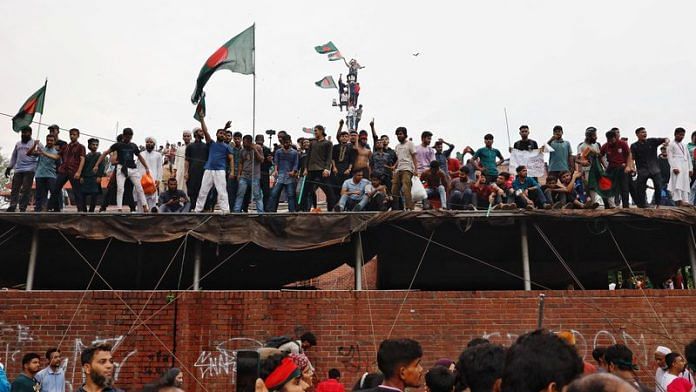 People waves Bangladeshi flags on top of the Ganabhaban, the Prime Minister's residence, as they celebrate the resignation of PM Sheikh Hasina in Dhaka, Bangladesh, August 5, 2024. REUTERS/Mohammad Ponir Hossain