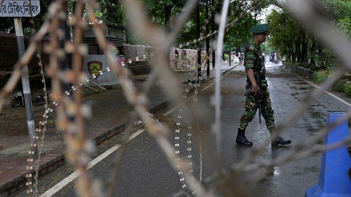 A security force personnel walks behind concertina wire placed across a road next to the residence of former Bangladeshi Prime Minister Sheikh Hasina, days after her resignation as the prime minister of the country, in Dhaka, Bangladesh, August 8, 2024. REUTERS/Fatima Tuj Johora/File Photo