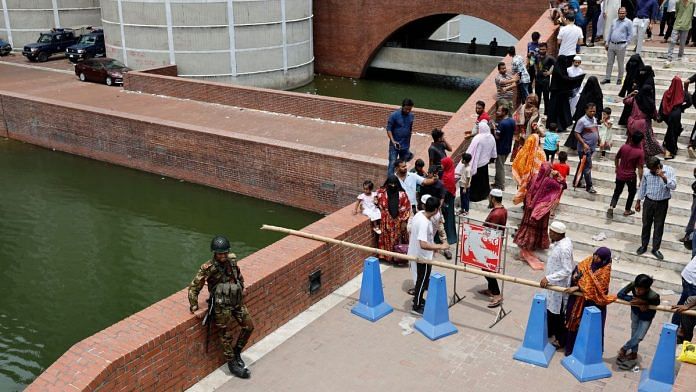 A member of the army stands guard as people gather at the entrance of the Parliament Building a day after the resignation of Bangladeshi Prime Minister Sheikh Hasina, in Dhaka, Bangladesh, August 6, 2024. REUTERS/Mohammad Ponir Hossain