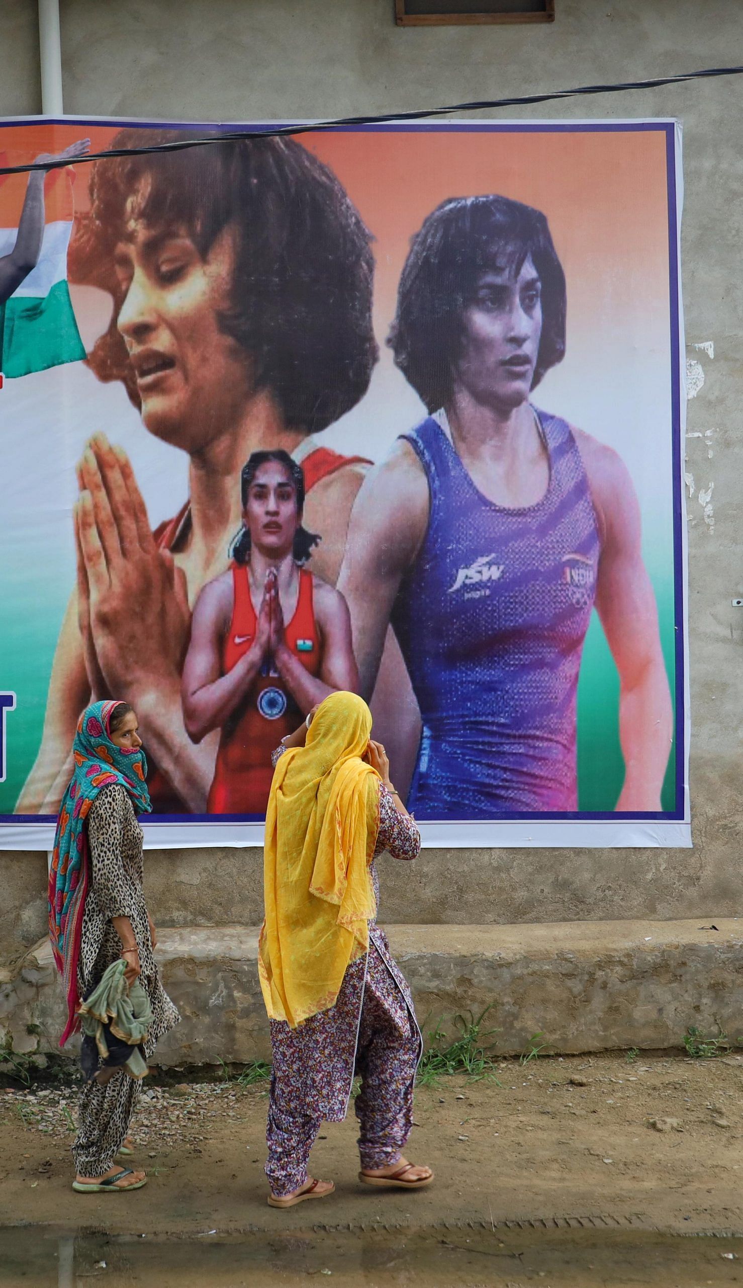 Women in the village keep on looking at Vinesh's posters as they walk past | Photo: Manisha Mondal | ThePrint