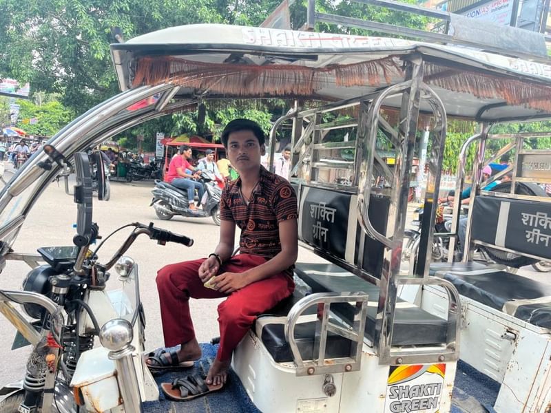कभी मुखर्जी नगर के चहल-पहल भरे माहौल का हिस्सा रहे ई-रिक्शा चालक छोटू सिंह, जो एक शांत दोपहर में यात्रियों का इंतजार कर रहे हैं. जैसे-जैसे छात्र और कोचिंग संस्थान दूर जा रहे हैं, उन्हें, कई अन्य लोगों की तरह, डर है कि जल्द ही उनके लिए यहाँ कुछ भी नहीं बचेगा. फोटो: नूतन शर्मा | दिप्रिंट