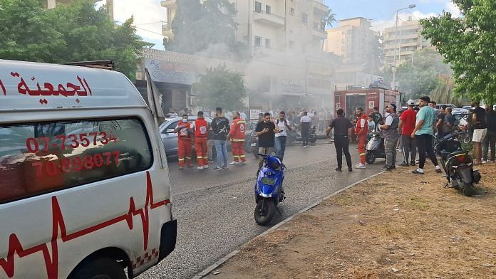 Smoke rises from a mobile shop as civil defence members gather in Sidon, Lebanon September 18, 2024. REUTERS/Hassan Hankir