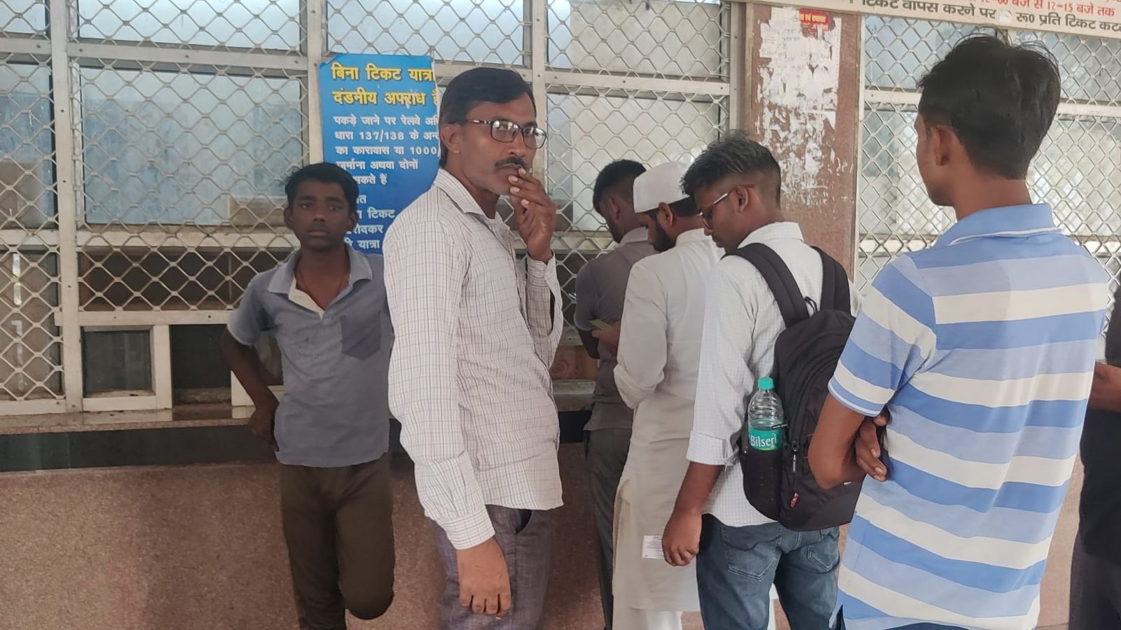 अतुल और उनके पिता राजेंद्र झारखंड के लिए टिकट खरीदने के लिए खतौली रेलवे स्टेशन पर लाइन में इंतज़ार करते हुए | फोटो: अलमिना खातून/दिप्रिंट