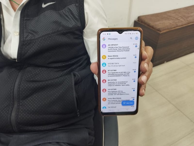 देवभूमि संघर्ष समिति के सह-संयोजक मदन ठाकुर अपने फोन पर एक आरटीआई अधिसूचना दिखाते हैं. उनका दावा है कि पिछले साल दायर की गई उनकी 10 आरटीआई क्वेरी का उन्हें अभी तक कोई जवाब नहीं मिला है | फोटो: हिना फ़ातिमा/दिप्रिंट