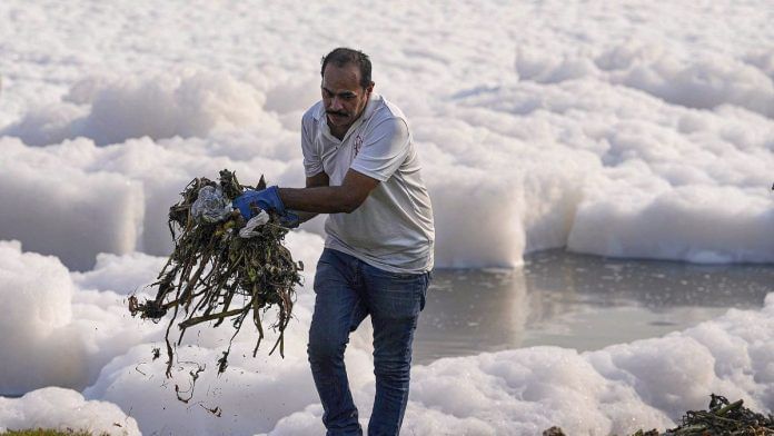A volunteer attempts to clean as toxic foam floats on the surface of the polluted Yamuna river, at Kalindi Kunj, in New Delhi, Saturday/PTI Photo/Ravi Choudhary