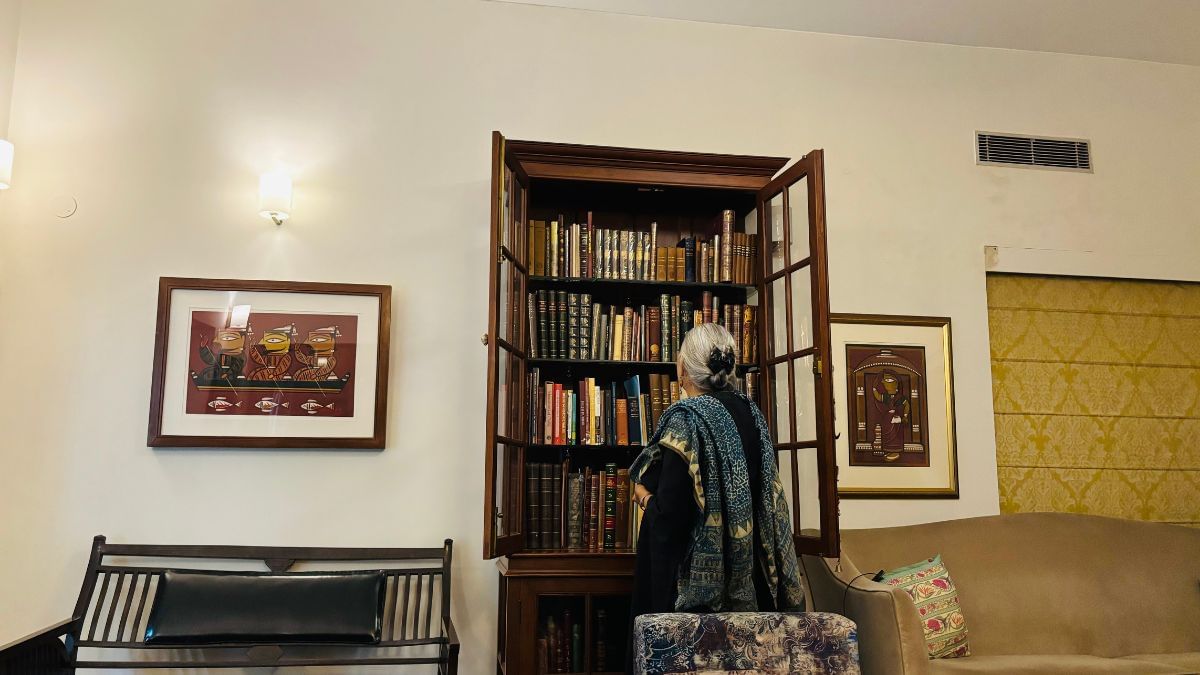 स्वप्ना लिडल, अपनी कीमती किताबों की अलमारी में से कुछ निकालती हुई | फोटो: वंदना मेनन/दिप्रिंट