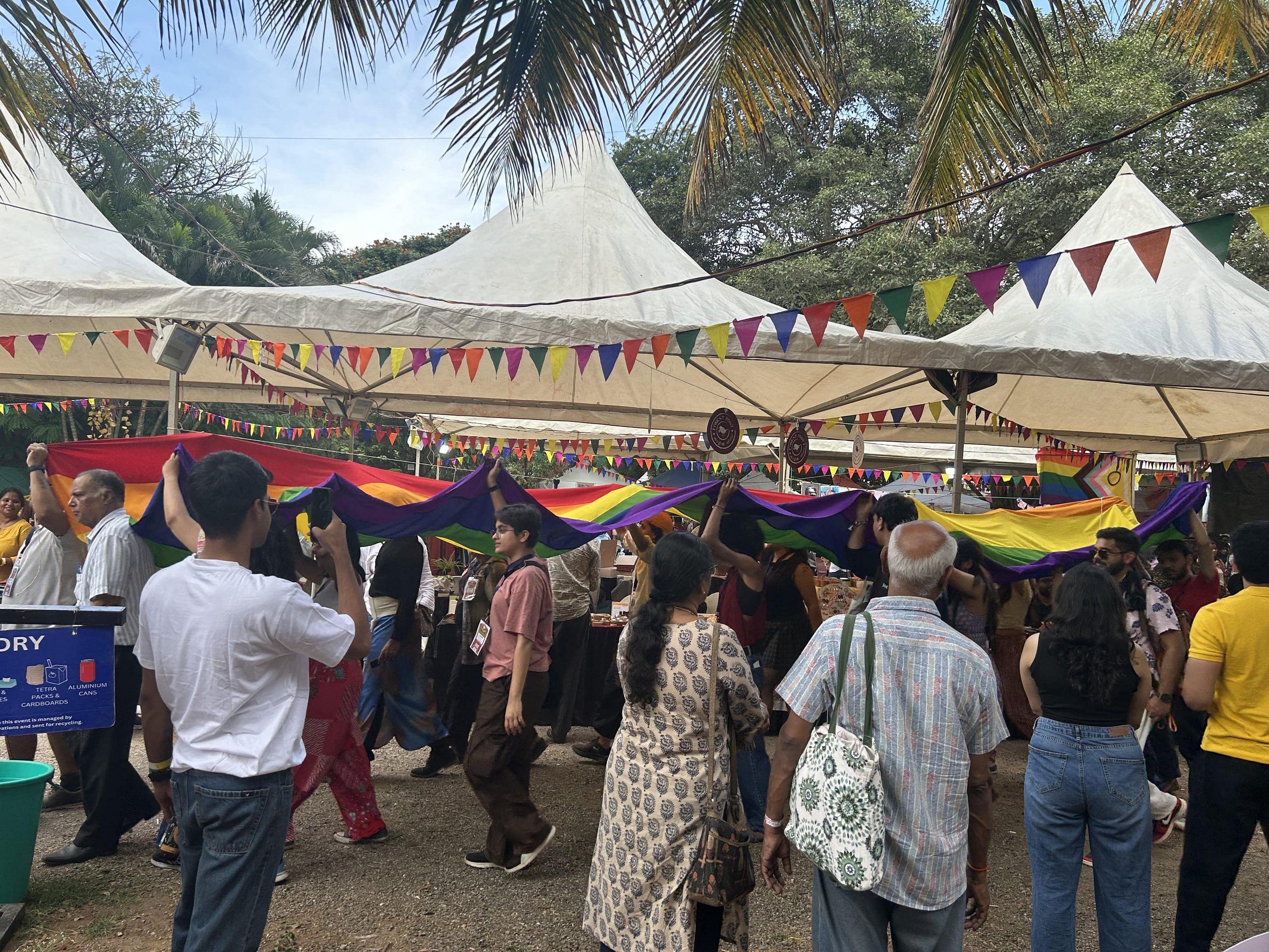 Families of LGBTQIA+ community members leading a pride march across the bazaar.