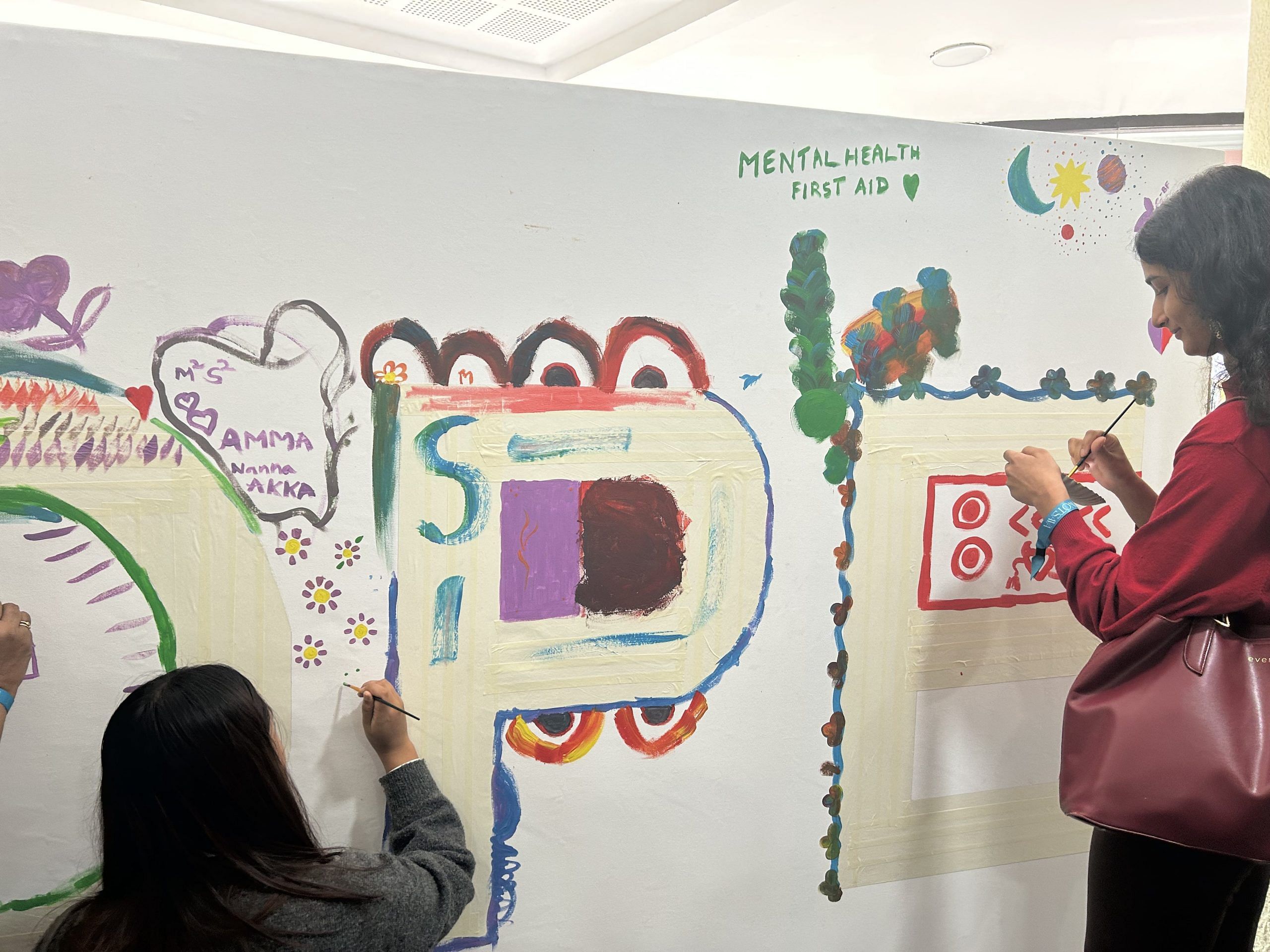 People painting their feelings on a big white canvas at NIMHANS convention centre