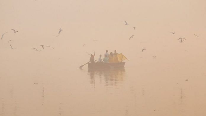 People take pictures on a boat on the Yamuna river on a smoggy morning in New Delhi, India, November 4, 2024. REUTERS/Anushree Fadnavis