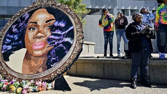 File photo of Tamika Palmer, the mother of Breonna Taylor, standing next to a painting of her daughter at a gathering to mark two years since she was killed at her Louisville home, on March 13 2022. | Reuters/Jon Cherry