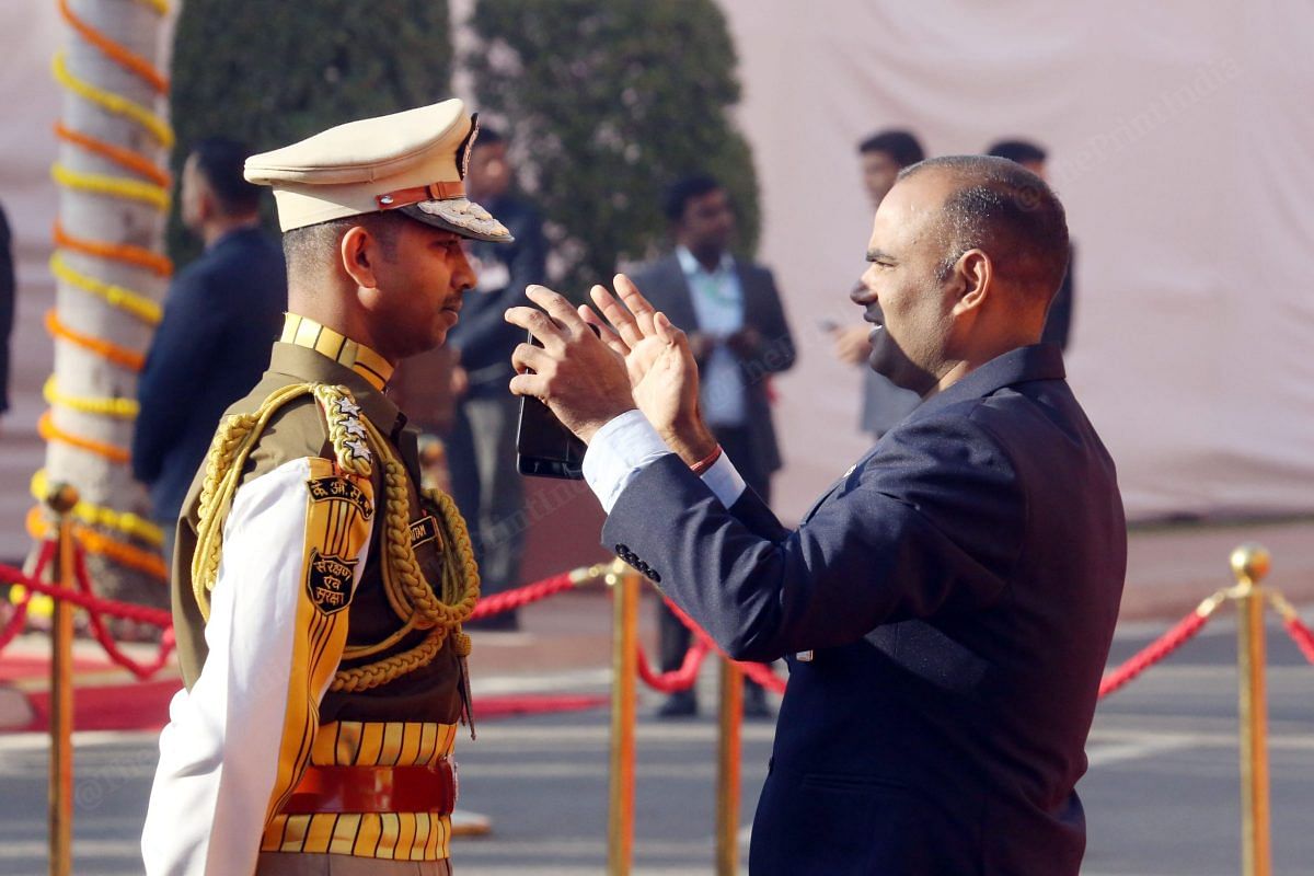 A security personnel helping a CISF personnel wear a cap at the Old Parliament House | Praveen Jain | ThePrint 