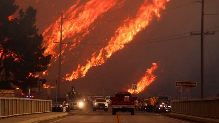 Flames rise behind vehicles as the Hughes Fire burns in Castaic Lake, California, US, Wednesday | Reuters/David Swanson