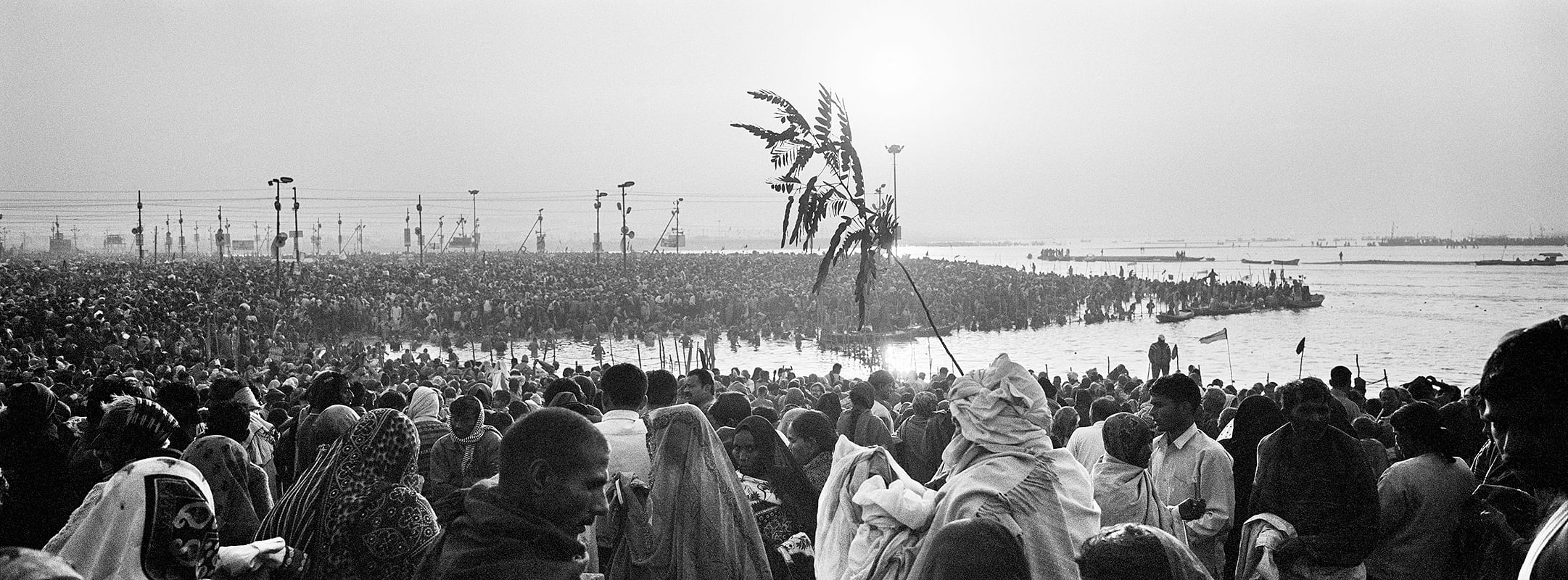 Ardh Kumbh Mela 2007: Pilgrims struggle to stay together following their groups makeshift symbols while women clutch on to family members sarees or shawls to avoid getting separated during the most auspicious bathing day of Mauni Amavasya. 