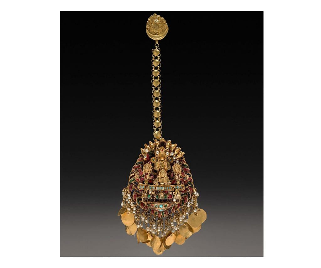 Forehead pendant with Sun God Surya in achariot with attendants; Kathmandu valley, Nepal; c. 1600–1700; Gold set with semi- precious stones; 8 x 4.6 cm; The Cleveland Museum of Art, Ohio