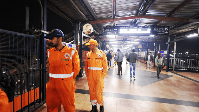 NDRF personnel keep a watch on the crowds from a footover bridge at New Delhi railway station | Manisha Mondal | ThePrint