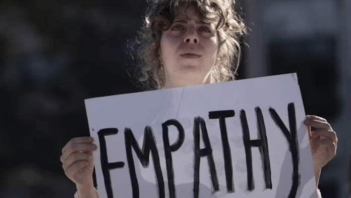 A woman holding a banner with empathy written on it | Representative Image | Via The Conversation