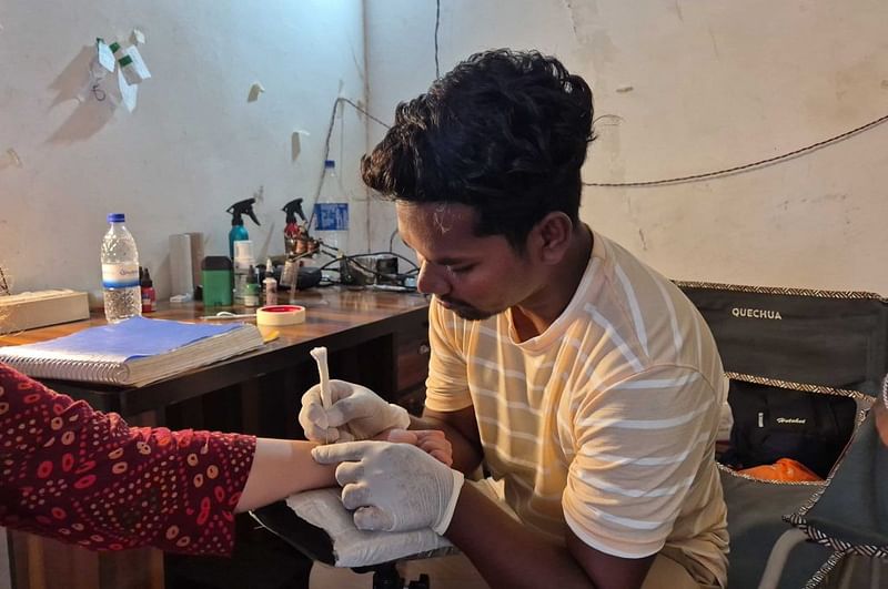 चित्रकोट में अपने स्टूडियो में एक ग्राहक को टैटू बनाते धरुजय बघेल | फोटो: शुभांगी मिश्रा