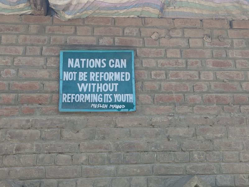 स्कूल के बाहर लगा हरे रंग का बोर्ड जिस पर सुधार और शिक्षा को बढ़ावा देने वाला मुहावरा लिखा है | फोटो: शरणवीर सिंह/दिप्रिंट