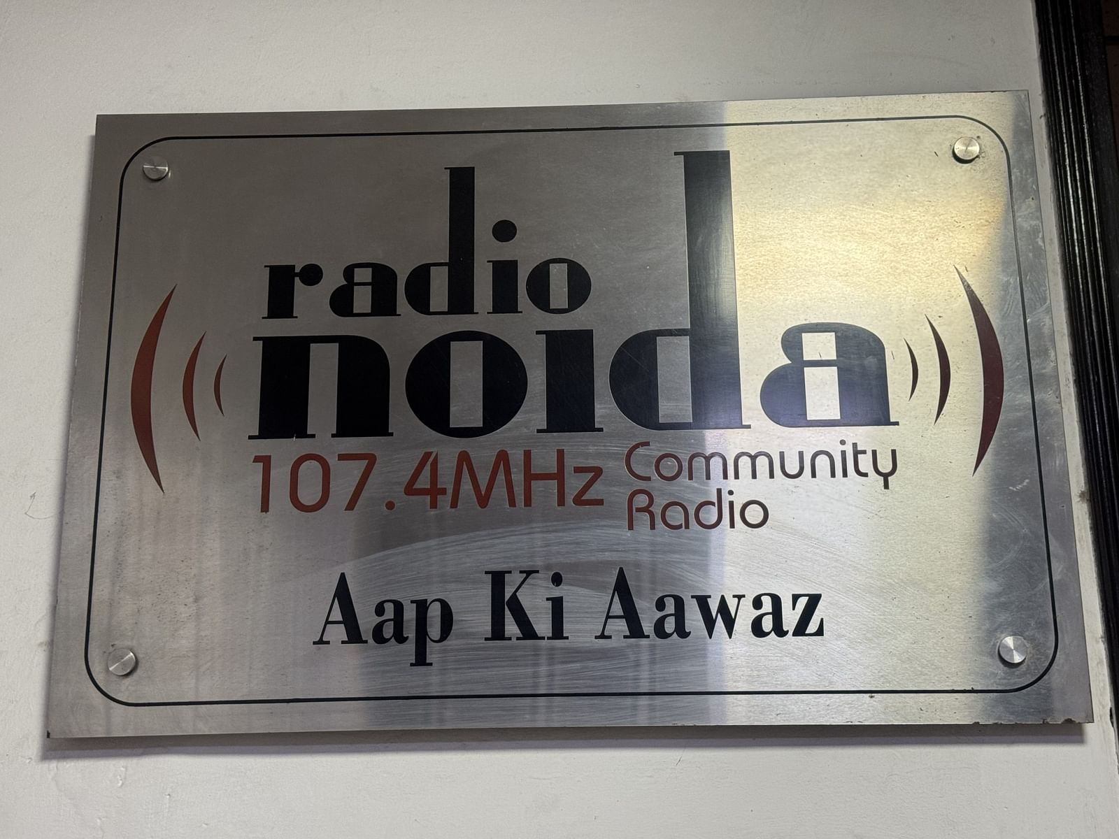 स्टेशन के बाहर एक बोर्ड लगा है, जिस पर लिखा है — “रेडियो नोएडा 107.4 MHz” — शहर का पहला और इकलौता कम्युनिटी रेडियो स्टेशन | फोटो: सागरिका किस्सू/दिप्रिंट