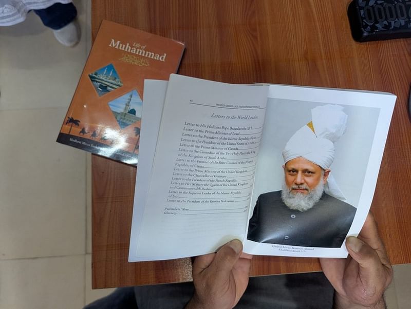 कॉलेज प्रोफेसर मोहम्मद अहमदिया साहित्य पढ़ते हैं. पहले पन्ने पर दुनिया भर में अहमदिया मुस्लिम समुदाय के वर्तमान आध्यात्मिक प्रमुख मिर्ज़ा मसरूर अहमद की तस्वीर है | फोटो: शरणवीर सिंह/दिप्रिंट