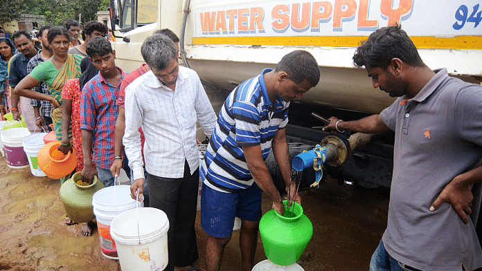 File photo of people standing in a queue to collect water from a tanker in Bengaluru | ANI